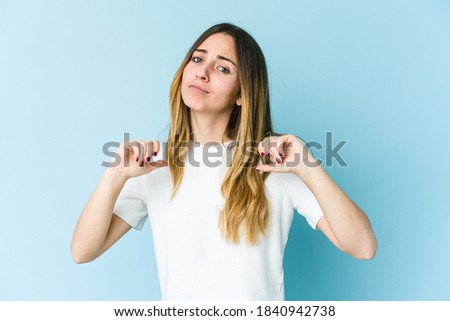 Young caucasian woman isolated on blue background feels proud and self confident, example to follow.