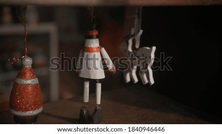 Little white Christmas toys deer soldier hanging on a thread behind glass in the house