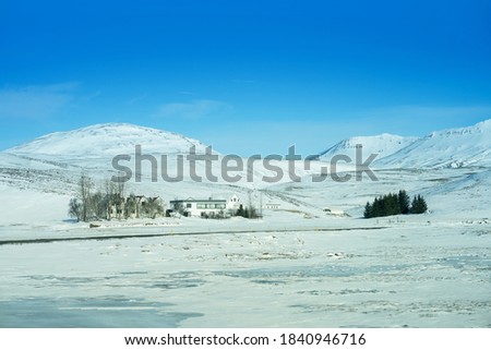Typical Icelandic landscape with Curving road covered snow and ice surrounded by white colour of snow on winter background of mountain with road leading to a little church and tall hill at Iceland