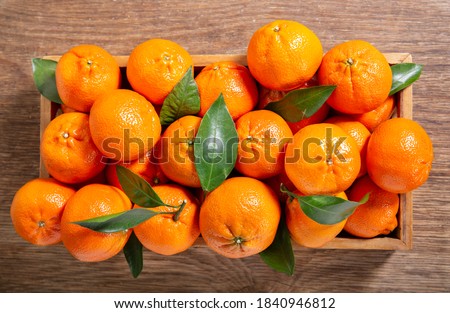 Fresh mandarin oranges fruit or tangerines with leaves in a wooden box, top view Royalty-Free Stock Photo #1840946812