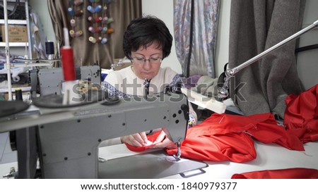 Woman master tailor works at a sewing machine in the studio