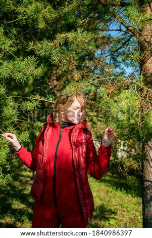 Happy woman with maple leaves in an autumn Park in a red jumpsuit.
