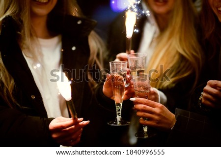 Caucasian young girls with champagne and lights on the street, cheerful company of girls and celebration, new year and christmas