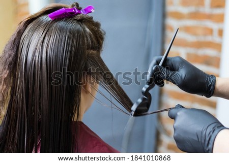 The Barber applies liquid keratin to the client's hair. Visit to a hair salon. The concept of hair care, keratin straightening and hair treatment. Royalty-Free Stock Photo #1841010868