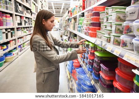 A girl chooses a container for food in a supermarket.