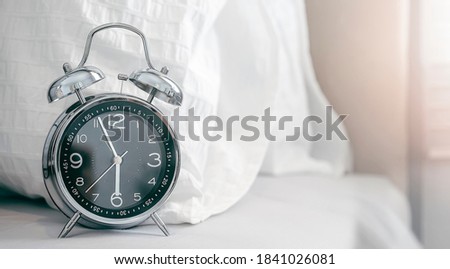 Vntage alarm clock on white bed. Time concept, copy space.