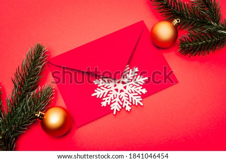 top view of snowflake, baubles, fir and envelope on red background