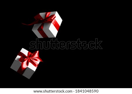 Discount background. White gifts with red bow falling on black background for Black Friday banner. Flying backdrop with space for text.