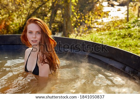 slim woman is relaxing in hot tub on fresh air, caucasian attractive female in bikini sits inside of bath