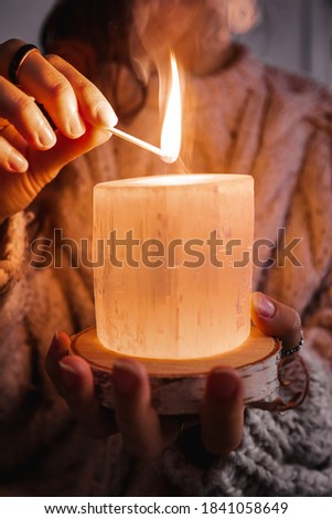hands of a woman holding and lighting a candle Royalty-Free Stock Photo #1841058649