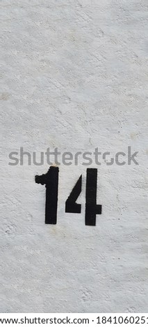 Black Number 14 on the white wall. Spray paint.