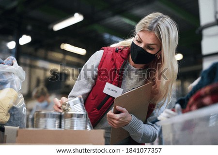 Woman volunteer in community charity donation center, food bank and coronavirus concept. Royalty-Free Stock Photo #1841077357