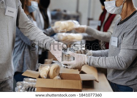 Group of volunteers in community donation center, food bank and coronavirus concept. Royalty-Free Stock Photo #1841077360