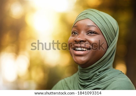 Portrait Of Laughing Black Muslim Lady In Hijab Standing Outdoors, Closeup Shot Of Happy Positive African Islamic Woman In Headscarf Looking Away And Sincerely Smiling, Selective Focus With Copy Space Royalty-Free Stock Photo #1841093314