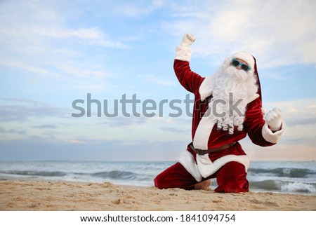 Santa Claus having fun on beach, space for text. Christmas vacation