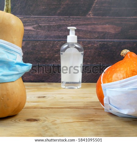 pumpkin wearing a face mask for protection from coronavirus and sanitizer. jack-o-lantern dance. Halloween 2020 concept, closeup