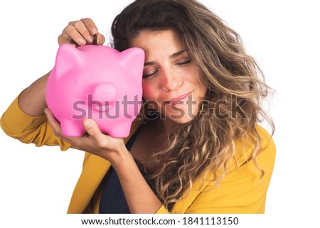 Portrait of young beautiful woman holding a piggy bank on studio. Isolated white background. Save money concept.