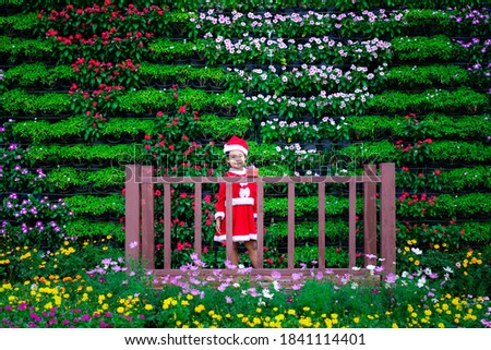 little asian girl in red Santa Claus costume with present box in the park