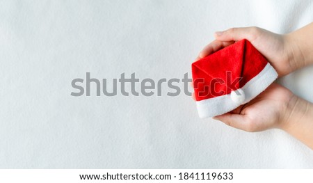 Hands holding santa hat on white background.Christmas winter celebration season party.gift, reward,Cloth fashion sale.share and donation.Christmas party surprise present.Holidays background.kid hand.