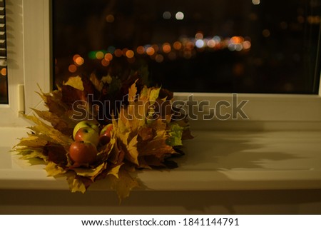composition of maple leaves, apples and candle.