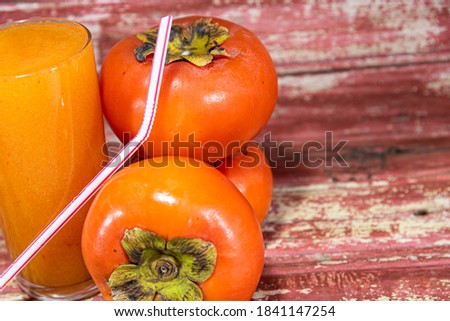 Persimmon fruits and juice. Construction wood background. Refreshing drink and detox. Juice rich in fiber and source of minerals. Natural food.