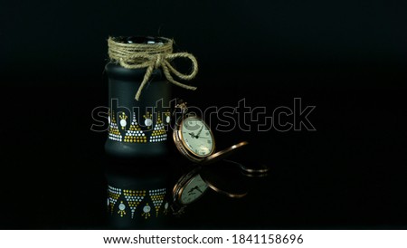 Beautiful mandala on a black glass bottle with a pocket watch with black background 