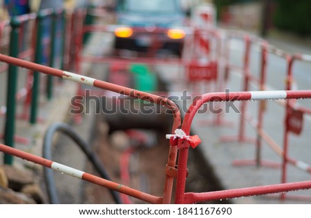Cordon off a civil engineering construction site in red and white and car in the blurred background with flashing hazard warning lights