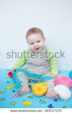 Closeup of a little infant boy in casual clothes playing in nursery with knitting wool