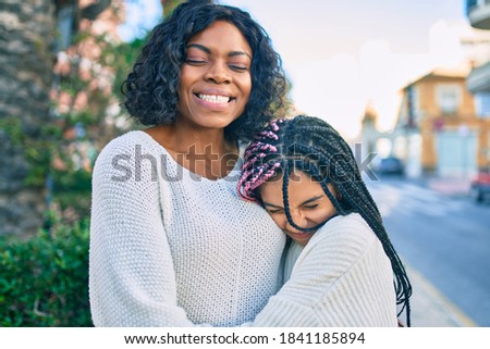 Beautiful african american mother and daughter smiling happy and hugging. Standing with smile on face standing at the park