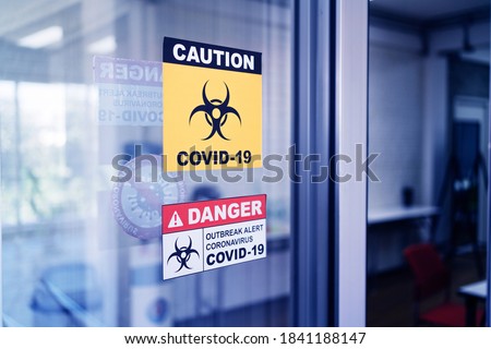Covid-19 Warning signs stick on the glass door. Quarantine and outbreak alert signs of coronavirus outbreak control.