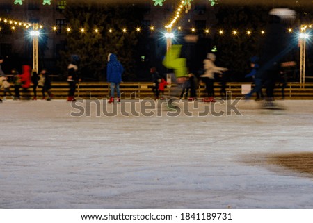 Night view of people enjoy ice skating on public rink