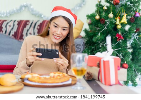 close up young asian woman holding smartphone to take picture of lunch meal on the table at inside home for christmas festival and celebration concept