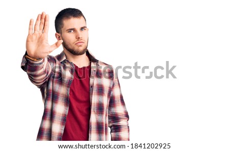 Young handsome man wearing casual shirt doing stop sing with palm of the hand. warning expression with negative and serious gesture on the face. 