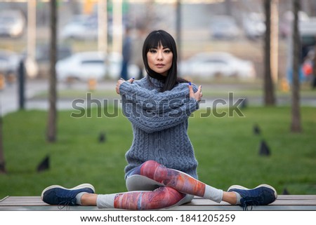 Beautiful asian woman seating on a bench  wearing knitted sweater