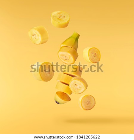 Fresh ripe baby bananas falling in the air isolated on yellow background. Food levitation concept. High resolution image Royalty-Free Stock Photo #1841205622