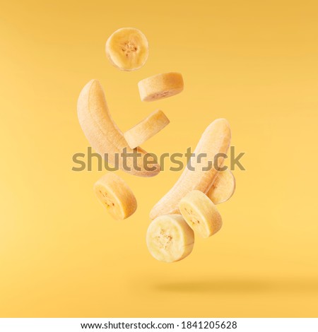 Fresh ripe baby bananas falling in the air isolated on yellow background. Food levitation concept. High resolution image Royalty-Free Stock Photo #1841205628