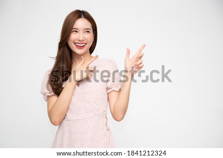 Young elegant beautiful Asian woman smiling and pointing to empty copy space isolated on white background Royalty-Free Stock Photo #1841212324