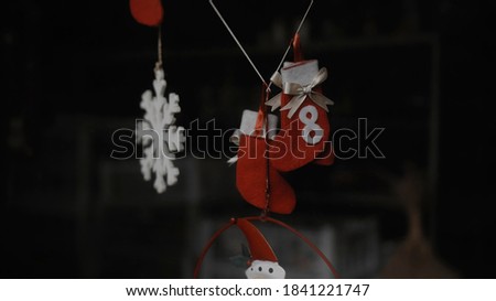 Small red christmas toy socks hanging on glass in the house