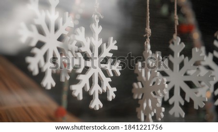 Little white Christmas jewelry snowflake hanging on a thread behind the glass in the house