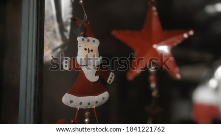 Small red Christmas toys santa claus standing behind the glass in the house