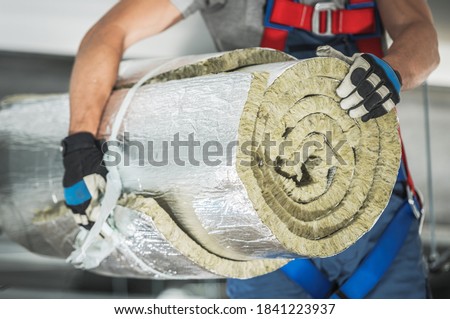 Caucasian Contractor Worker in His 40s with Roll of Mineral Wool Insulation in His Hands Preparing For Commercial Building Walls Insulation. Royalty-Free Stock Photo #1841223937