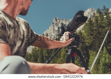 Caucasian Photographer in His 40s Preparing His Photo Camera Equipment For Landscape Photography in Scenic Mountains Area.