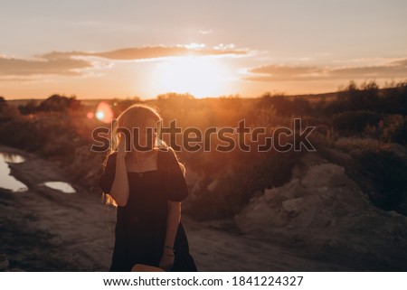 Portrait of boho woman in hat posing in summer countryside in evening. Atmospheric moment