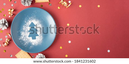 Christmas tree on scattered flour on a plate on a red background. Cookies and cones near the plate. Place for your text.