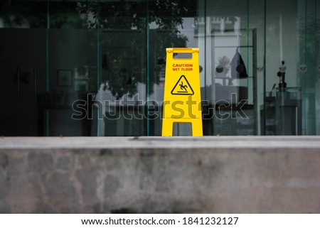 Yellow caution wet floor signage on sement.glass wall background