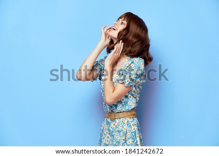 Woman in fashionable dress look ahead hands near the face stylish clothes 