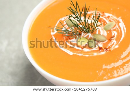 Delicious pumpkin soup in bowl on grey table, closeup