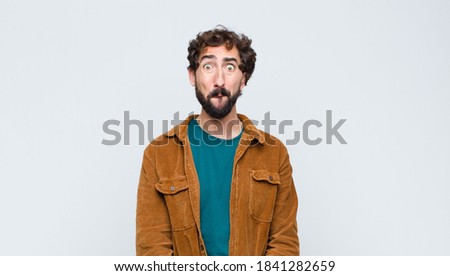 young handsome man feeling sad and stressed, upset because of a bad surprise, with a negative, anxious look against flat wall