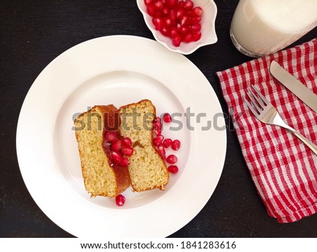 Photo of sweet slice cake and pomegranate seeds on the top. Picture of sweet breakfast.
