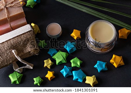 Cosmetics, handmade flower soap, face and body cream, natural material washcloth on a black background. Spa home.